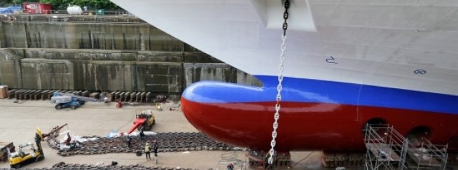 Workers are dwarfed by the Crown PrincessÍs massive anchor chains.   Photograph By ADRIAN LAM, Times Colonist